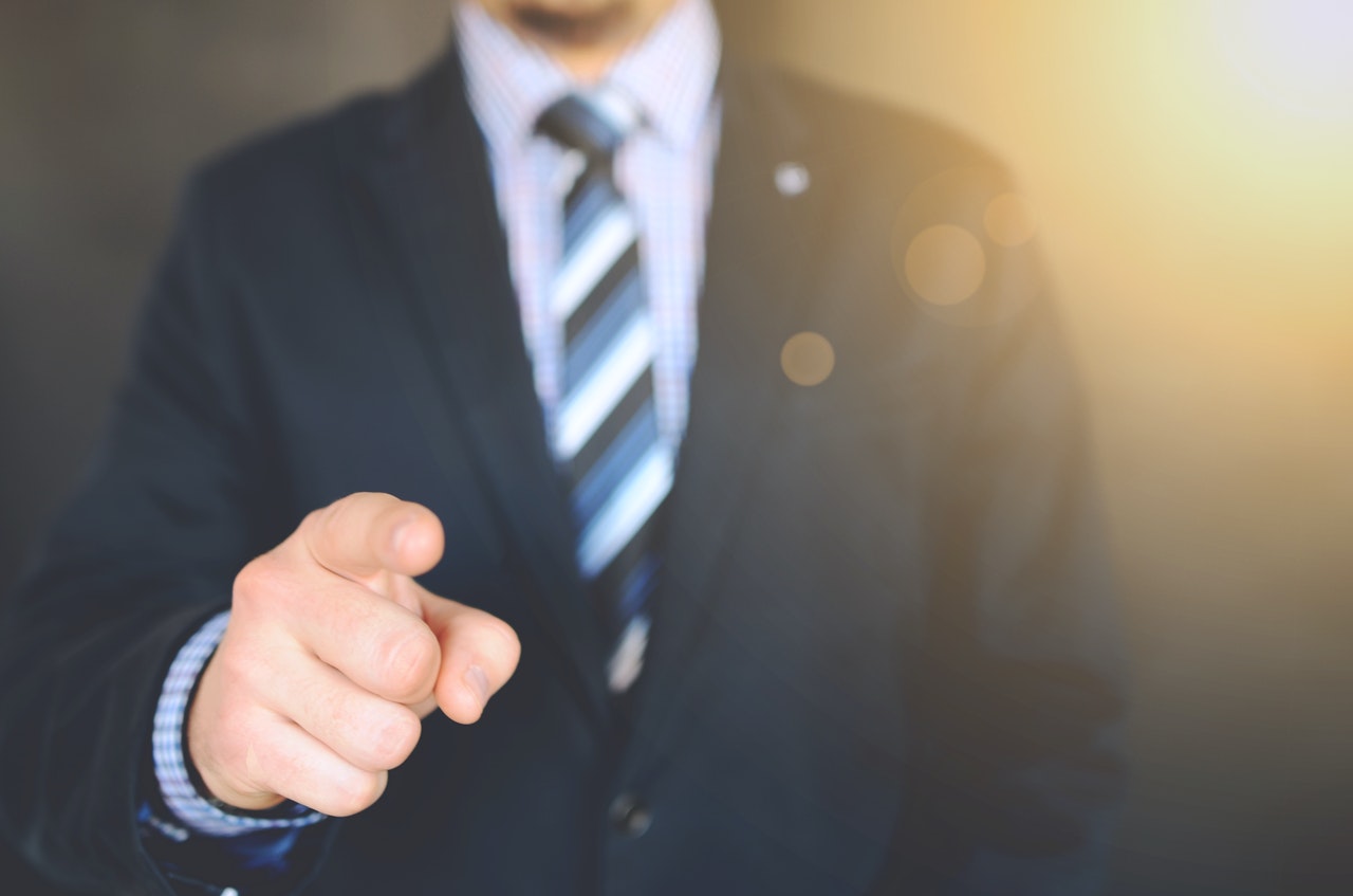 Banner of an executive in suit pointing towards the reader.